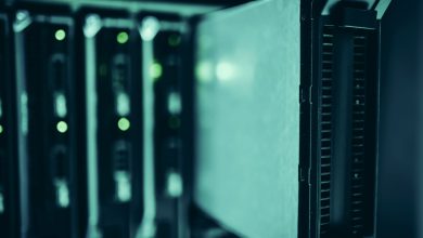 Fileiras de racks de servidores iluminadas em azul dentro de um data center moderno.