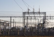 Subestação elétrica com estruturas metálicas e linhas de alta tensão ao amanhecer.
