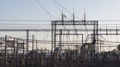 Subestação elétrica com estruturas metálicas e linhas de alta tensão ao amanhecer.