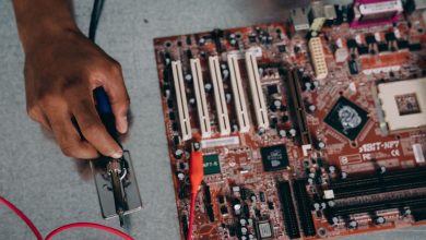Profissional utilizando uma ferramenta de solda em uma placa-mãe durante trabalho de desenvolvimento de hardware.