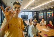 Equipe reunida em um escritório moderno, colaborando diante de um quadro de vidro com anotações.