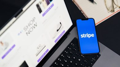 Smartphone exibindo um aplicativo de pagamentos diante de um laptop com um site de comércio eletrônico aberto.