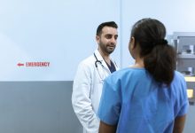 Médicos e enfermeiros conversam diante da área de emergência de um hospital.