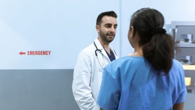 Médicos e enfermeiros conversam diante da área de emergência de um hospital.