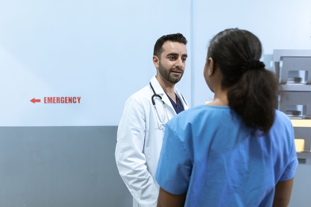 Médicos e enfermeiros conversam diante da área de emergência de um hospital.