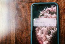 Smartphone exibindo um alerta de fraude sobre uma superfície de madeira.