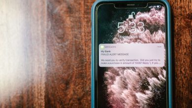 Smartphone exibindo um alerta de fraude sobre uma superfície de madeira.